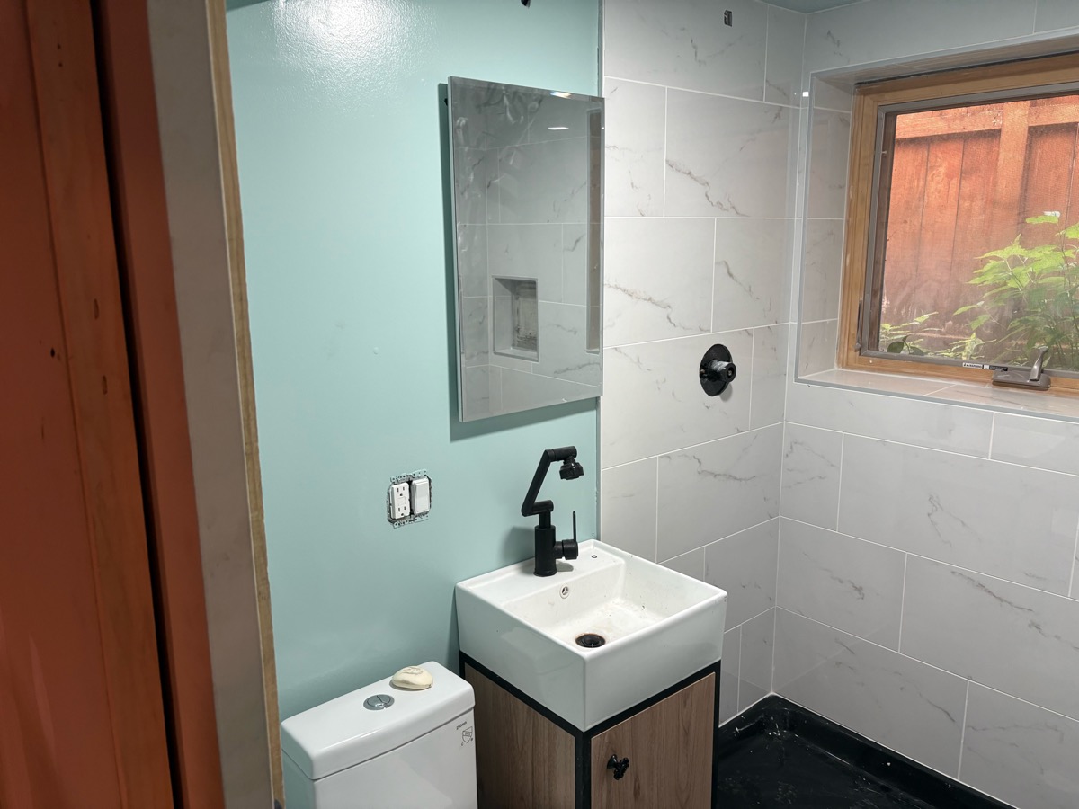 Completed bathroom remodel with marble-look tile and black fixtures