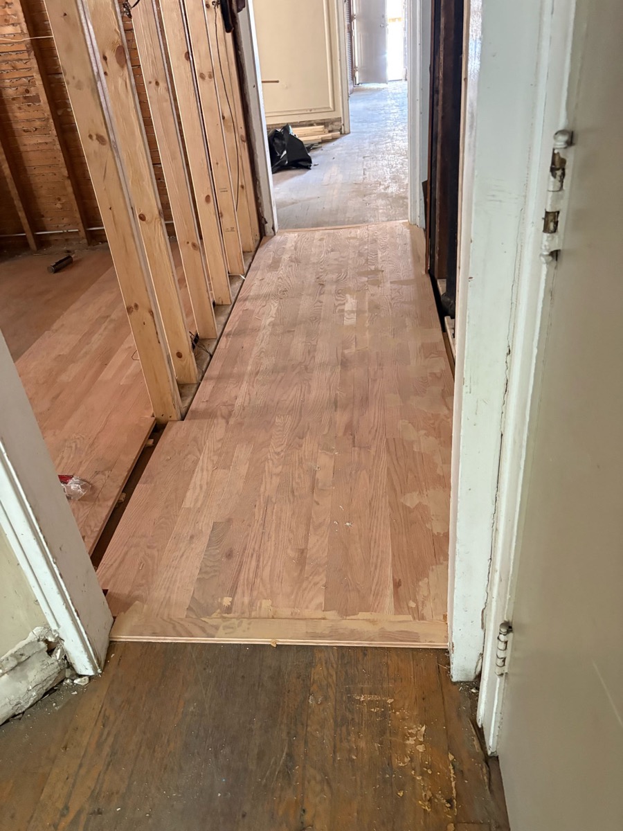 New hardwood flooring installed in a hallway, matched to existing wood floor