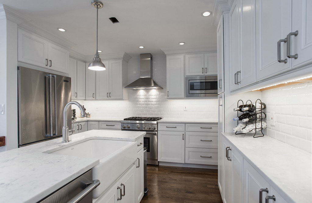 Modern white kitchen remodel with marble countertops and stainless appliances